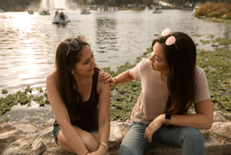 Zwei Frauen sitzen an einem See. Eine Frau könnte fragen: "Braucht mein Kind Logopädie?"